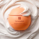 Avon Her Wisdom Baobab whipped oil body cream in a rounded orange jar, surrounded by a swirl of thick white whipped cream.