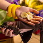 Close-up of hands holding sliced bananas and a small lizard with a blurred background